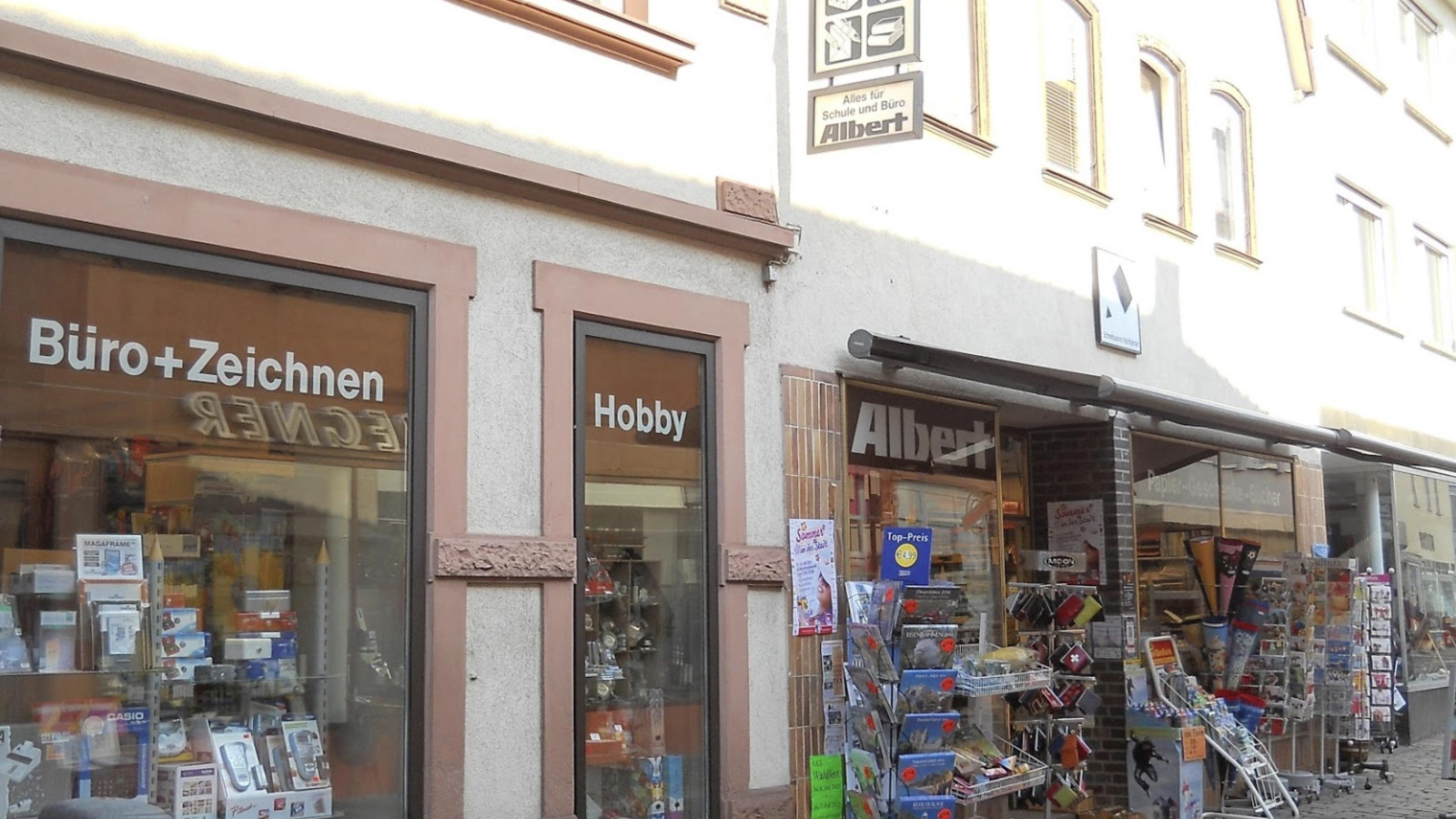 Außenansicht eines Geschäfts mit Schaufenstern, die Büro- und Hobbyartikel zeigen.