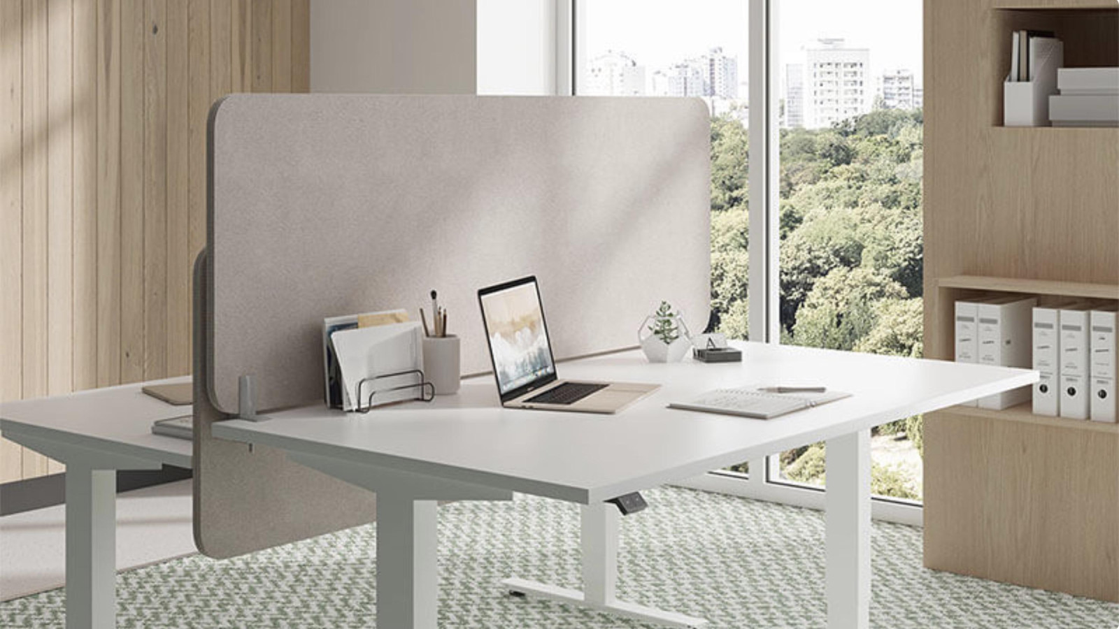 Zwei moderne Schreibtische in einem Büro mit Trennwand und Blick aus dem Fenster auf die Stadt.