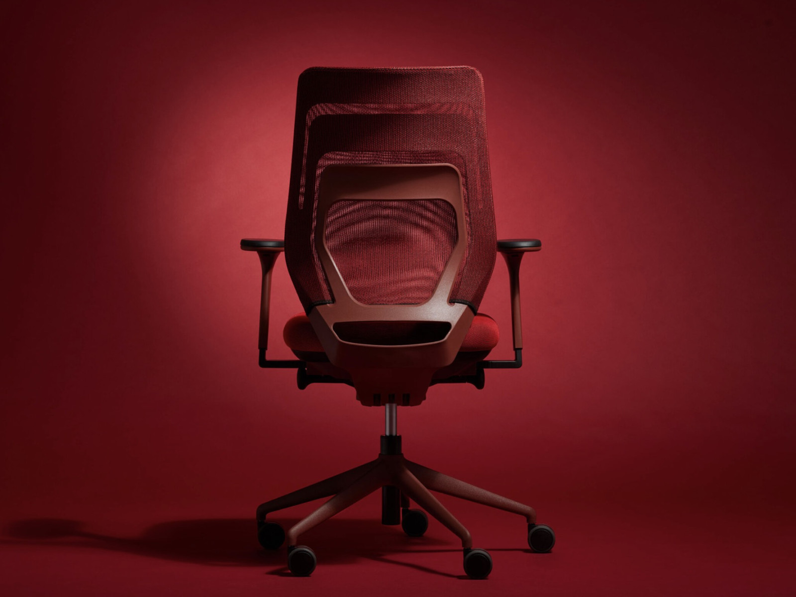 Bürostuhl mit Mesh-Rückenlehne, von hinten, rot beleuchteter Hintergrund.