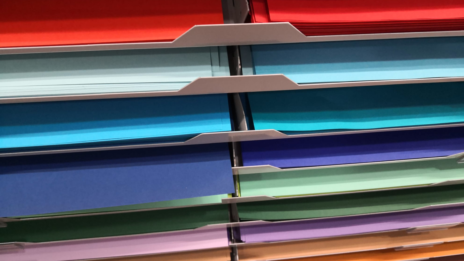 Regale mit buntem Papier in verschiedenen Farben arrangiert.