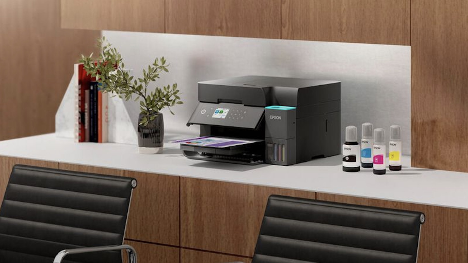 Epson Multifunktionsdrucker auf Schreibtisch mit Pflanzenvase, Büchern und Tintenflaschen.